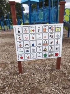 3 foot by 3 ft white board with pictures and words mounted in a playground.